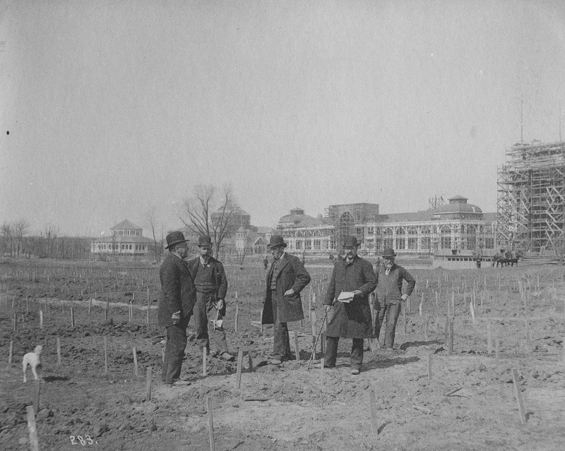 People in field with stick during Columbian Exposition construction. Description: People in field with stick during Columbian Exposition construction; Chicago, IL. Source: ICHi-52246. Chicago History Museum. Reproduction of photographic print, photographer unknown. Date: early 1890s.